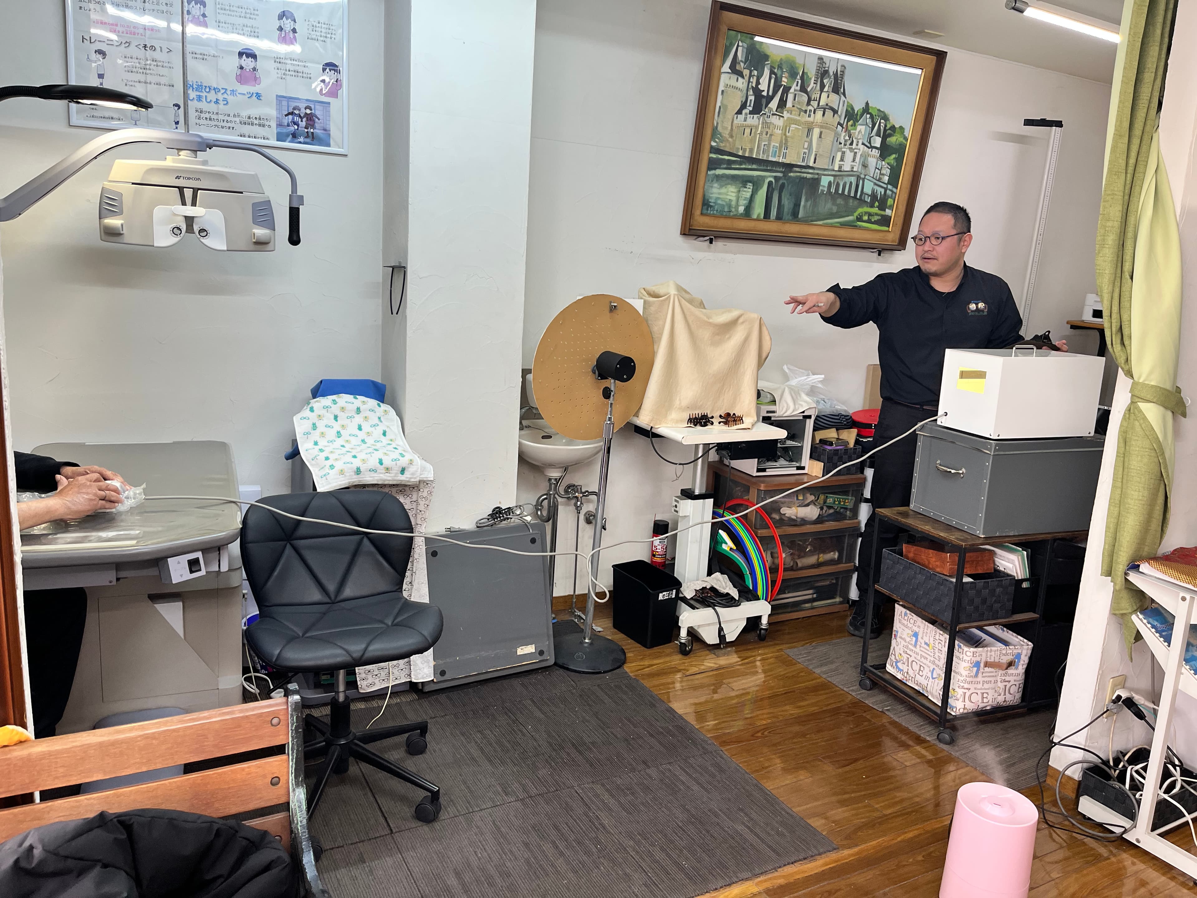 検査機器やトレーニング用具がある店内で説明するスタッフ